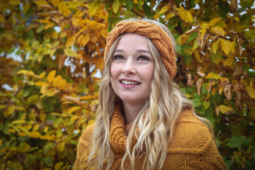 Portrait blonde frau mit locken  mit hund im herbst vor strauch mit stirnband und poncho 