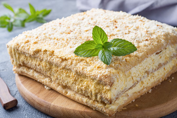 Layered cake with cream Napoleon millefeuille vanilla slice with mint on dark background.