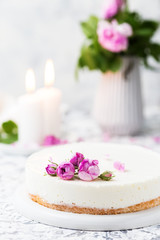 Fototapeta na wymiar Beautiful white cake decorated pink roses and candles on a white table. Romantic evening