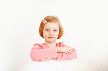 Fototapeta premium Red-haired girl in a pink T-shirt and bow in her hair on the white background