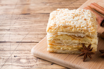 Layered cake with cream Napoleon millefeuille vanilla slice with cinnamon and anise on wooden background.