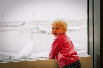 Fototapeta na wymiar cute little girl looking at planes in airport, kids travel