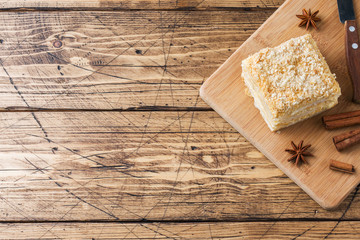 Layered cake with cream Napoleon millefeuille vanilla slice with cinnamon and anise on wooden background.