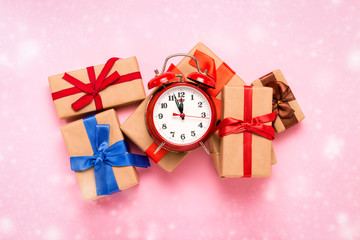 Gift boxes and a red alarm clock on a light pink background. Merry Christmas and Happy New Year concept. Flat lay, top view © Alex