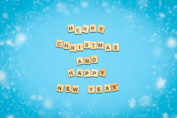 Text of Happy Christmas and Happy New Year laid out of wooden plates with letters on a blue background. Minimalism. Flat lay, top view