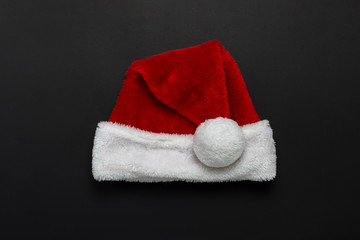 Obraz na płótnie Canvas Santa Claus hat on a black background. The concept of New Year and Merry Christmas. Minimalism. Flat lay, top view