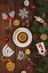 The winter holidays. Christmas tree toys on a brown wooden table. Happy New Year. Hot cup of tea. Top view