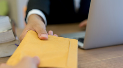 close up businessman hand sending or receive secret tan envelope form partner in private room , anti corruption concept