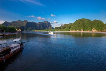 Fototapeta premium Sea background, vivid blue wallpaper, natural scenery (mountains, fishing boats), a common habitat between people and nature.