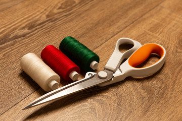 Colourful thread spools and scissors on work bench.