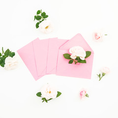 Valentines day composition with roses and pink paper cards on white background. Flat lay, top view.