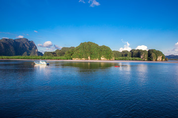 Fototapeta premium Sea background, vivid blue wallpaper, natural scenery (mountains, fishing boats), a common habitat between people and nature.