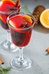 Two glassses witn winter Christmas traditional mulled wine with orange slices, anise and cinnamon sticks among winter decorations.