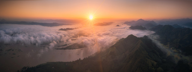 Beautiful dramatic sunset in the mountains Between Thailand-Laos. Landscape with sun light shining through orange clouds