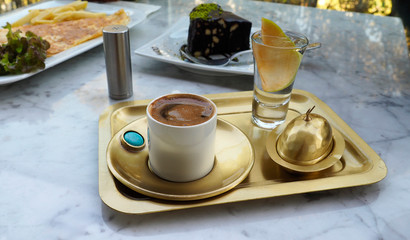 Turkish coffee on a bronze tray. Concept of breakfast with Turkish coffee, scrambled eggs and chocolate cake.
