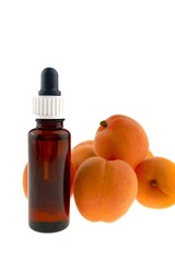 apricot oil in a bottle of  glass with a pipette and fresh apricots isolated on white background
