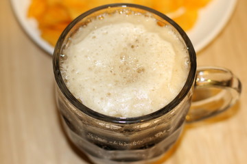 Foamy black beer and crispy chips on white plate