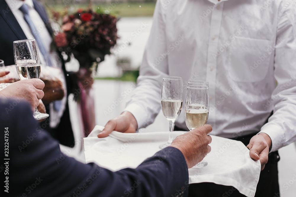 Wall mural waiter holding tray with glasses of champagne and serving them for toasts wedding reception. people 