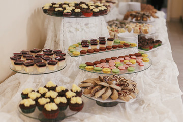 Delicious table with desserts and macarons at wedding reception in restaurant. Candy bar. Luxury wedding catering
