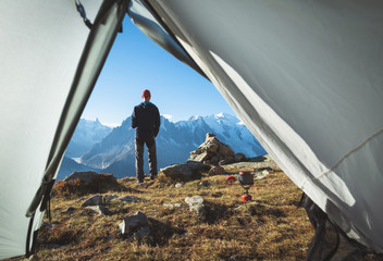 Hiker enjoying the view and a cup of coffee at his campsite on the famous Tour du Mont Blanc.