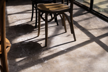 close up wooden chair legs with shadow and light on grunge cement ground