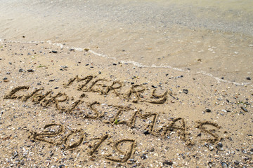 Merry Christmas written on tropical beach sand, copy space. Holiday concept