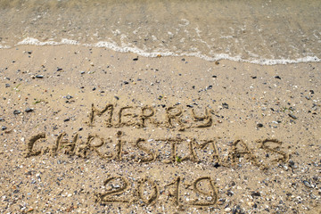 Merry Christmas written on tropical beach sand, copy space. Holiday concept, top view