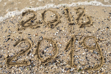 New Year 2019 replace 2018 on the sea beach concept, copy space. Wave starting to cover digits 2018. New Year 2019 is coming concept