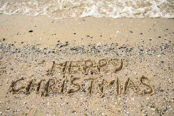 Merry Christmas written on tropical beach sand, copy space. Holiday concept, top view
