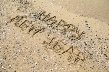 Happy new year written on tropical beach sand, copy space. Holiday concept