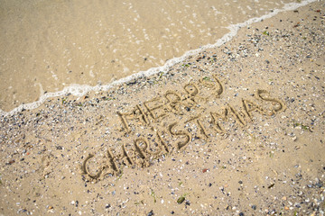 Merry Christmas written on tropical beach sand, copy space. Holiday concept, top view