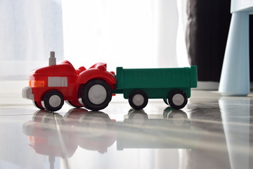 zabawka traktor z przyczepa na podłodze