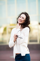 Fototapeta premium Young woman, against background of summer city. Woman thinking concept with beautiful curly hair 