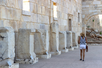 Fototapeta na wymiar Woman promenades in the ancient historical structures and observe old columns information