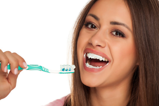 young woman brushing her teeth with tooth brush on white background