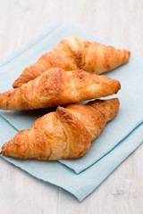 Tasty buttery croissants on old wooden table.