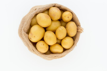 Sack of fresh raw potatoes on wooden background, top view