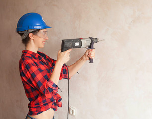 Woman builder worker with drill standing against white background. Construction. Building tools