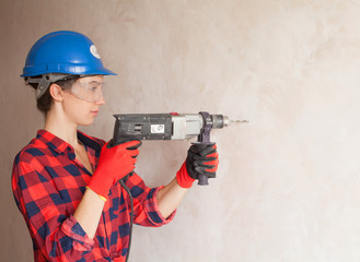 Woman builder worker with drill standing against white background. Construction. Building tools