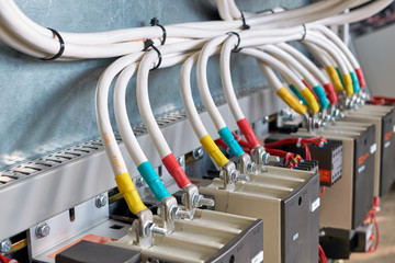 A large bundle of electrical cables or wires connected to contactors. High-power magnetic starters. Connection using a bolted connection. Large electrical Cabinet. Modern and reliable equipment.