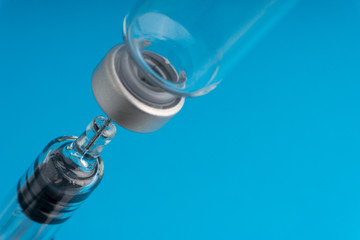 Medical syringe and vial on blue background with selective focus and crop fragment