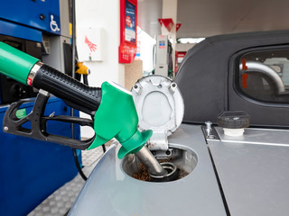 Pump refilling car with fuel at gas station