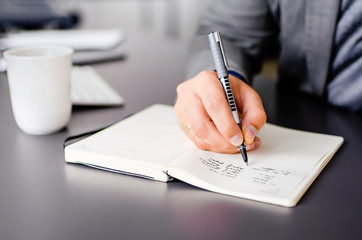 An entrepreneur  taking down notes in a notebook