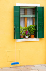 Italy, Burano, a window with flowers on the yellow wall of the house