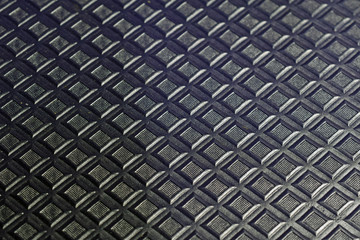 Black / dark blue small embossed squares on black background. Abstract wallpaper backdrop. Shallow depth of field.