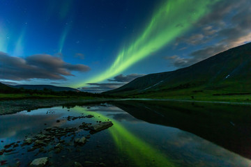 Fototapeta na wymiar aurora borealis in the night sky cut the mountains, reflected in the water.