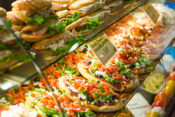Varied sandwiches and pizza on the counter of a street cafe