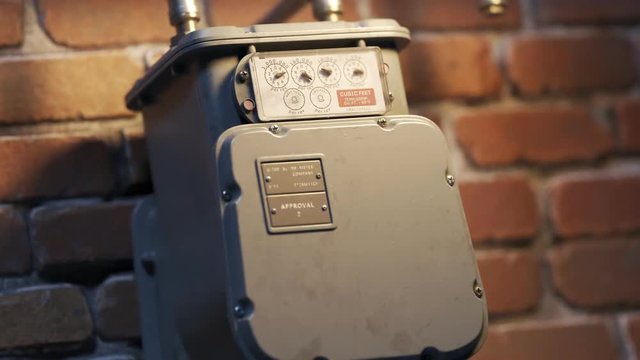 Vintage gas meter on brick wall with slow zoom to dial close-up
