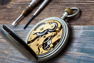 vintage clock with an open mechanism and two screwdrivers