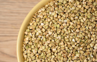 Natural fresh green buckwheat in ceramic bowl on wooden background.